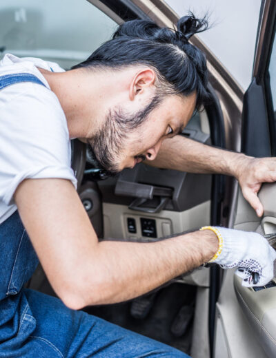 Fixing car engine in automobile repair garage. Handsome mechanics in uniform are repairing car while working in auto service